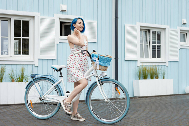 Beyaz bisikletli şirin bir lezbiyen ve kovası var. Yaz mevsiminde güney yakasında. - Fotoğraf, Görsel