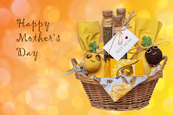 Mothers day greeting card. Closeup of a gift basket with Mediterranean spice mixes with a Best Mom tag, chocolate and other presents on abstract yellow background with Happy mother day inscription. - Fotoğraf, Görsel