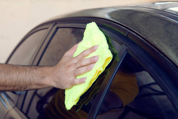 Un homme essuie une voiture avec un chiffon - Photo, image