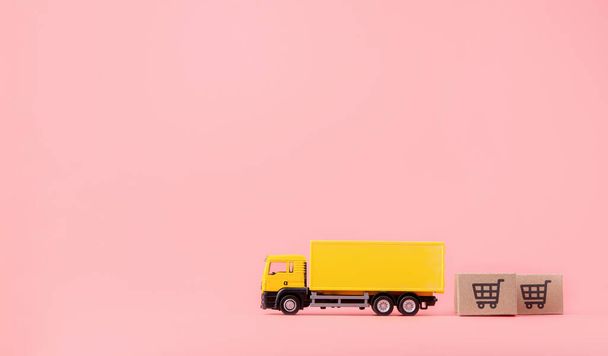 Logistica e servizio di consegna Cargo truck e cartoni di carta o pacchi con un logo carrello della spesa su sfondo rosa. Servizio shopping sul web online e offre consegna a domicilio. con spazio di copia - Foto, immagini