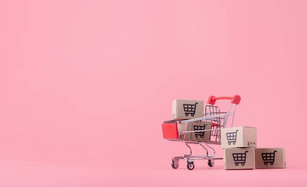 Concept d'achat : Cartons ou boîtes en papier en panier rouge sur fond rose. achats en ligne les consommateurs peuvent acheter à domicile et le service de livraison. avec espace de copie - Photo, image