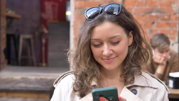 Mensajes de mujer joven en smartphone y bebidas café en la cafetería - Metraje, vídeo