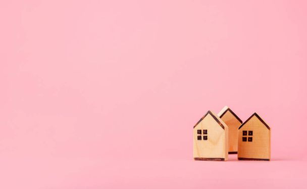 Rahansäästö- ja investointikäsite. Puiset talot vaaleanpunainen tausta kopioi tilaa - Valokuva, kuva