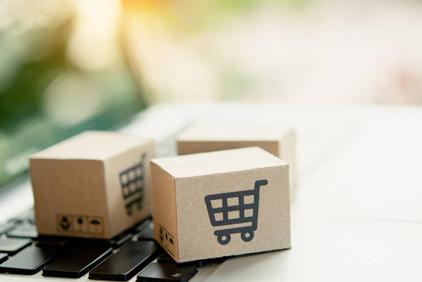 Online einkaufen. Karton mit einem Warenkorb-Logo auf der Laptop-Tastatur. Shopping-Service im Internet. bietet Lieferung nach Hause. Kopierspac - Foto, Bild