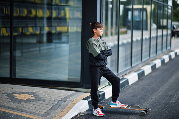 Teenager boy in a sports suit with longboard. - Photo, image