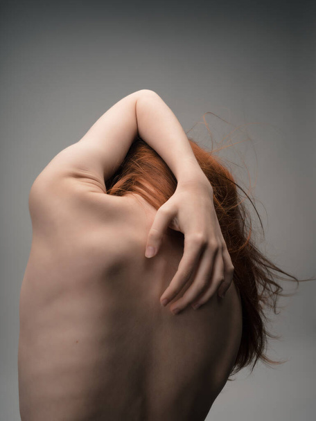 woman with red hair stands back ribs figure - Zdjęcie, obraz