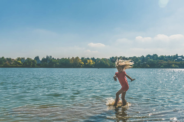 one child splashing water while running in the water - Valokuva, kuva