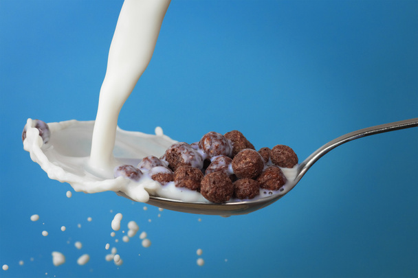 Milk splashing into spoon with chocolate cornballs - Zdjęcie, obraz