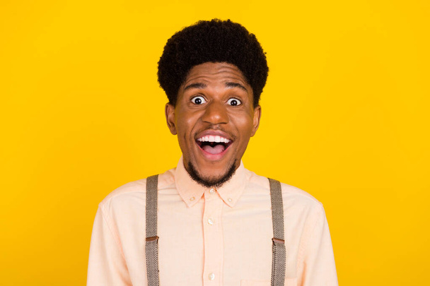 Photo of excited amazed surprised african guy open mouth wear suspenders shirt isolated yellow color background - Fotoğraf, Görsel