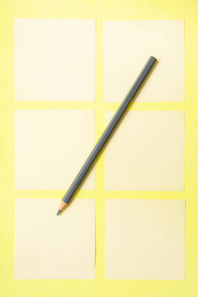 grauer Bleistift auf gelbem Hintergrund mit leeren Notizen zum Schreiben von Erinnerungen - Foto, Bild