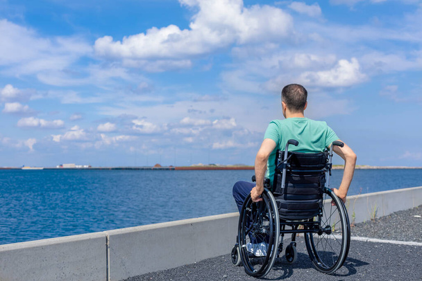 Behinderter Mann im Rollstuhl, der das Meer bewundert. Reise, Mobilität und Freiheitskonzept. - Foto, Bild