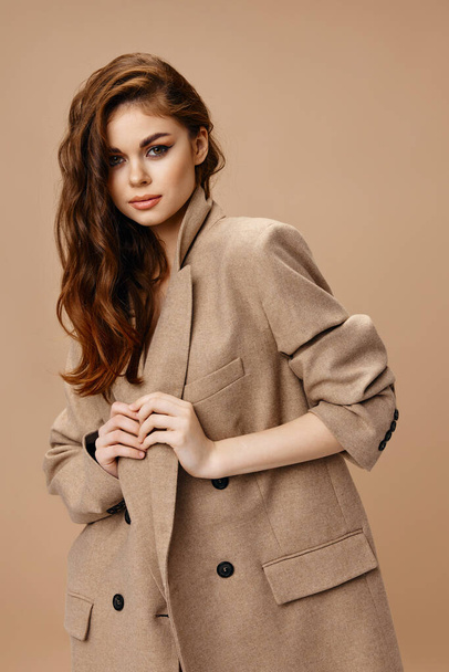 pretty brunette woman in coat touches collar with hands - Fotoğraf, Görsel