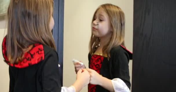 blonde six ans fille se préparant pour Halloween dans le couloir à l'intérieur de la maison, peignant son visage en regardant miroir - Séquence, vidéo