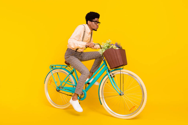Full length body size photo man riding bike with flowers basket in glasses isolated vivid yellow color background - Photo, Image
