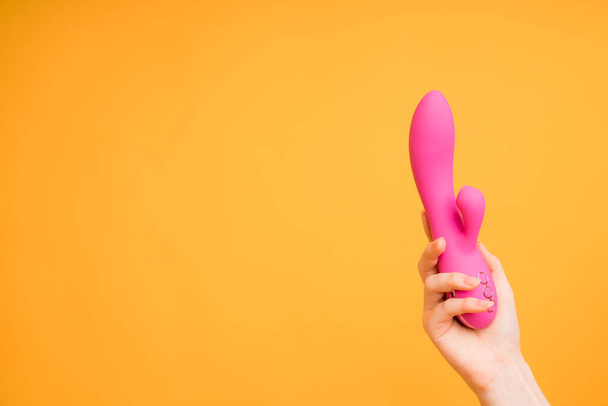 A pink dildo lies in the girls hand with a massager for the clitoris. Useful for a sex shop - Foto, Imagen
