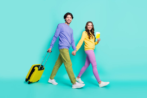 Full size profile side photo of young couple happy smile go walk registration flight tickets bag isolated over teal color background - Fotografie, Obrázek