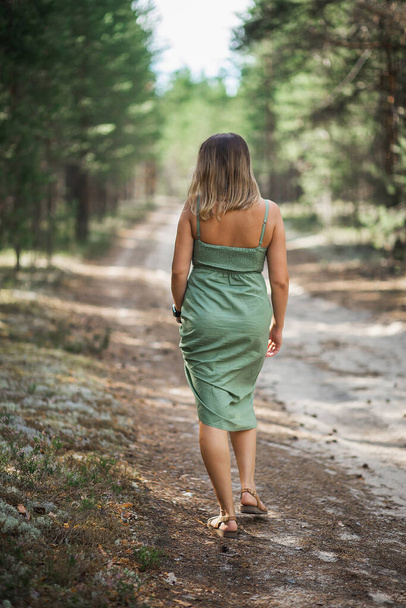 A beautiful girl with flying hair in a pine forest. Good forest witch in a green dress - Valokuva, kuva