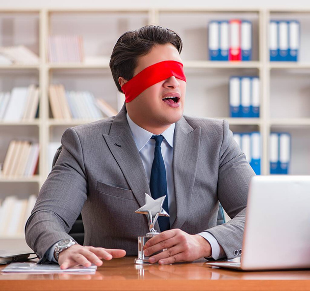 Geschäftsmann mit verbundenen Augen sitzt im Büro am Schreibtisch - Foto, Bild