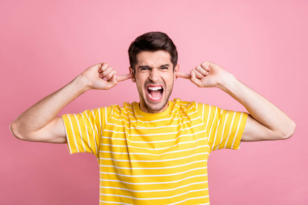 Portrait of attractive crazy fury guy yelling closing ears fight break up isolated over pink pastel color background - 写真・画像