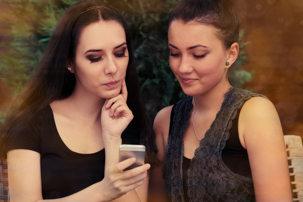 Young Women Looking at Smart Phone Screen - 写真・画像