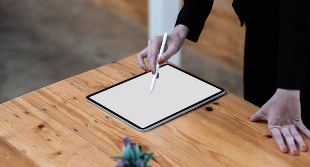 Cerca de la mano de la mujer de negocios de escritorio dibujo en una tableta de computadora de pantalla blanca en blanco - Foto, imagen