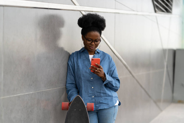 Afro amerykańska dziewczyna smsowanie lub przeglądanie w aplikacji smartfona na zewnątrz korzystać 5g łącze internetowe - Zdjęcie, obraz