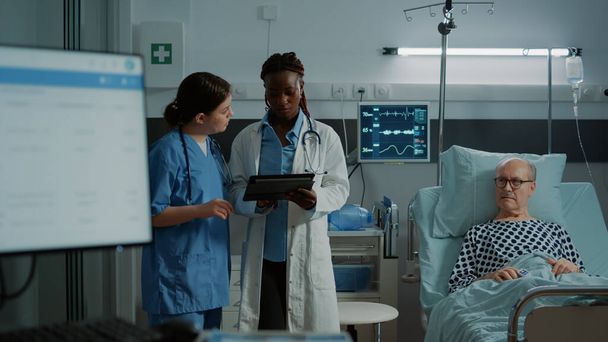 Enfermera multiétnica y médico mirando tableta para las pruebas - Foto, imagen