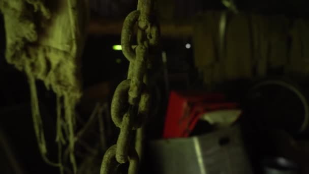Cadenas oxidadas cuelgan del techo y cuelgan en un sótano abandonado, una cadena de metal y gancho se mueven en un antiguo granero - Metraje, vídeo