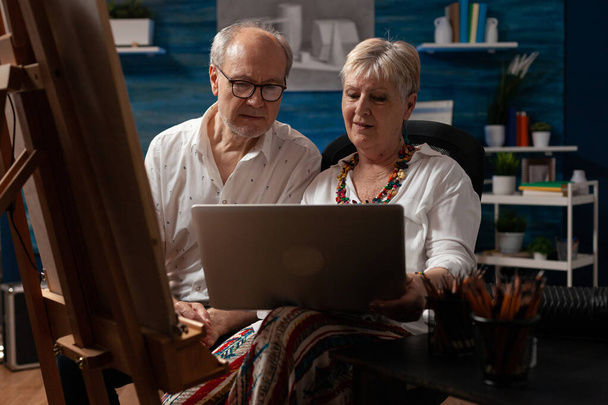 Kaukasisches älteres Ehepaar schaut mit Technik auf Laptop - Foto, Bild