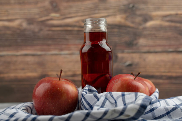 Deliciosas manzanas rojas y vaso de jugo rojo sobre mantel rayado. Foto de alta calidad - Foto, Imagen