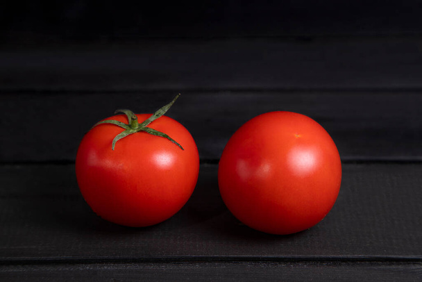 Delicious red tomatoes placed on dark wooden surface. High quality photo - Photo, Image