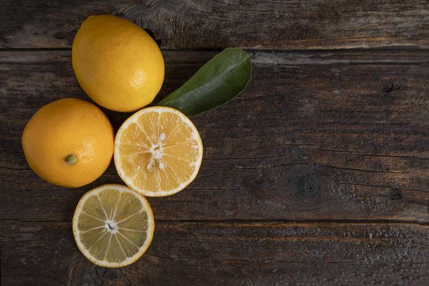 Fresh lemon fruits with leaves placed on a wooden table . High quality photo - Fotografie, Obrázek