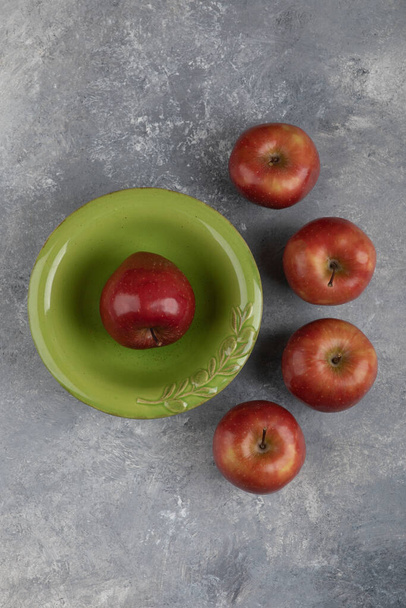 Πράσινο μπολ με μονό κόκκινο μήλο σε μαρμάρινη επιφάνεια. Υψηλής ποιότητας φωτογραφία - Φωτογραφία, εικόνα