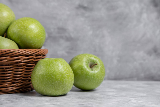 A wicker basket of perfect fresh green apples on a stone background . High quality photo - Valokuva, kuva