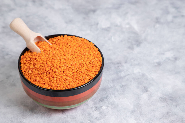 Uma tigela cheia de grãos de lentilha vermelha crua com uma colher de madeira. Foto de alta qualidade - Foto, Imagem