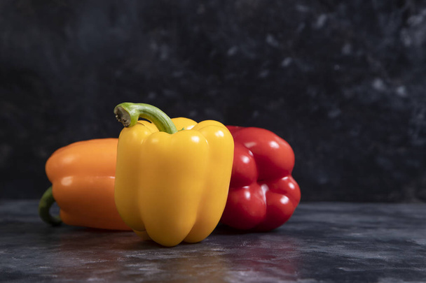 Πολύχρωμες υγιείς πιπεριές τοποθετούνται σε ένα πέτρινο φόντο. Υψηλής ποιότητας φωτογραφία - Φωτογραφία, εικόνα
