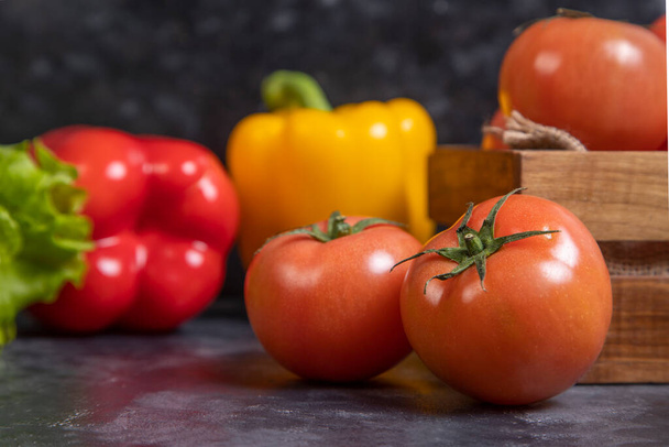 Yellow and red bell peppers with juicy tomatoes in a wooden old box . High quality photo - Foto, Imagem