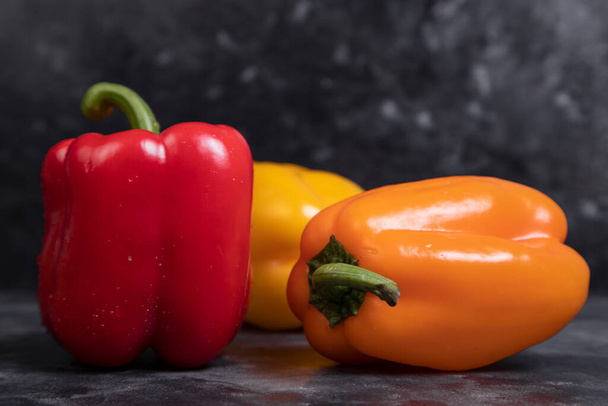 Πολύχρωμες υγιείς πιπεριές τοποθετούνται σε ένα πέτρινο φόντο. Υψηλής ποιότητας φωτογραφία - Φωτογραφία, εικόνα