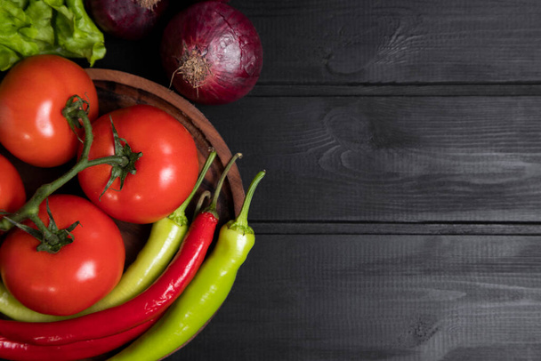 A wooden bowl full of fresh red juicy tomatoes with green and red chili peppers . High quality photo - Foto, Imagem
