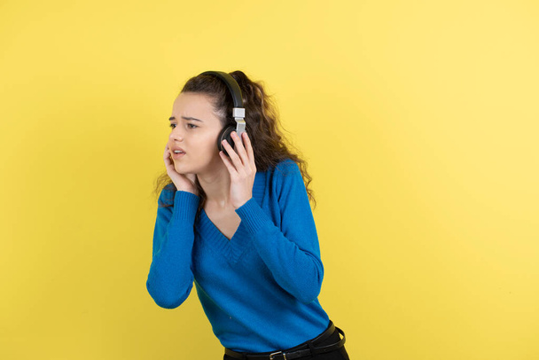 Photo of beautiful young girl in headphones trying to listen someone. High quality photo - Foto, afbeelding
