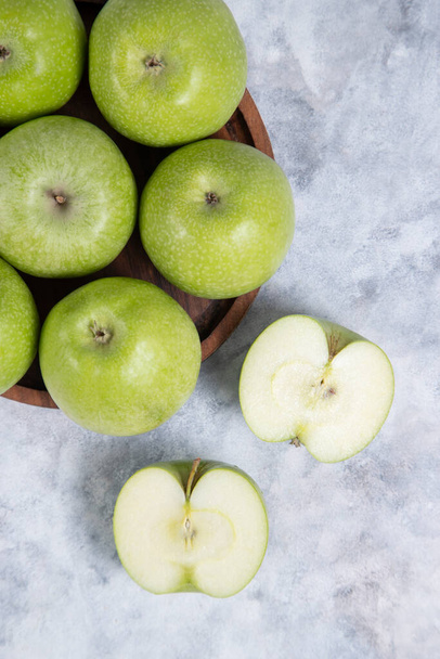 Drewniana płyta z całych i pokrojonych w plasterki świeżych dojrzałych owoców zielonych jabłek. Wysokiej jakości zdjęcie - Zdjęcie, obraz