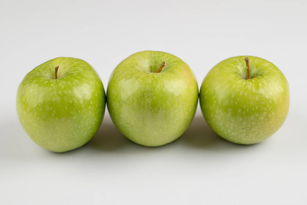 Kolme tuoretta vihreää omenaa sijoitettu valkoiselle pohjalle. Laadukas kuva - Valokuva, kuva