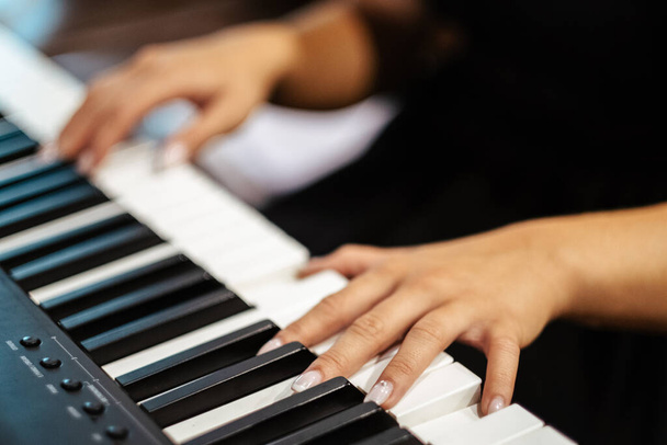 A closeup of female hands playing a digital piano - Фото, зображення
