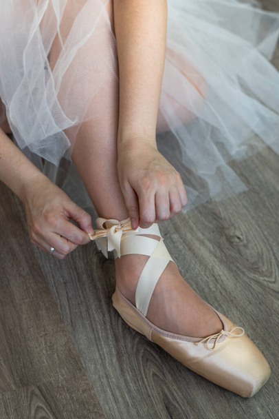 legs of girl dancing ballet with tulle skirt and pink shoes different dance steps wooden floor and white background with copy space - Fotografie, Obrázek