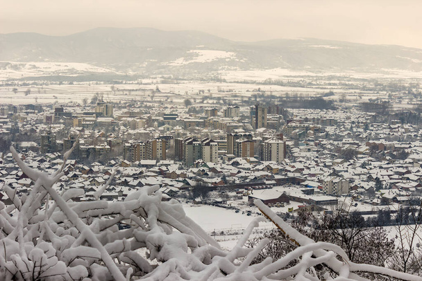 Het besneeuwde Pirot stadsgezicht omlijst met bevroren takken - Foto, afbeelding