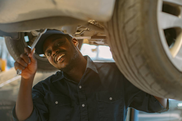 African maintenance male checking car with use wrench , service via insurance system at Auomobile repair and check up center - 写真・画像