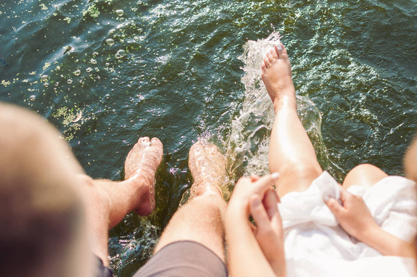 A closeup shot of a cute couple wetting their feet in the water - Фото, зображення