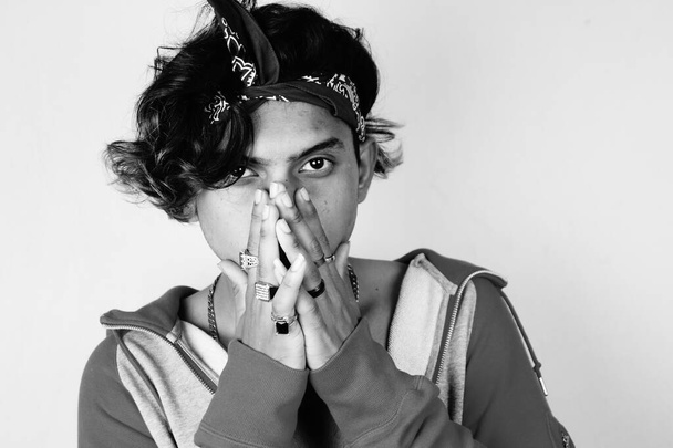 A grayscale shot of a young Indian male posing for the camera with hands on the face - Foto, Imagen