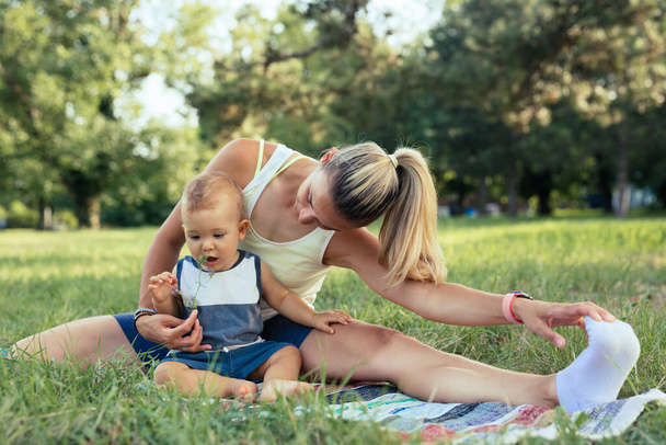 mother with her baby boy doing physical exercises outdoors - Foto, imagen