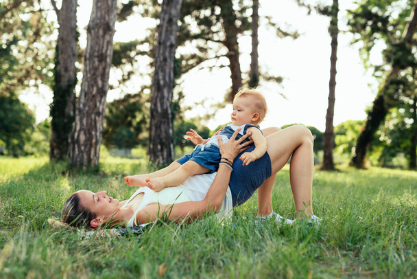 mother with her baby boy doing physical exercises outdoors - Foto, imagen